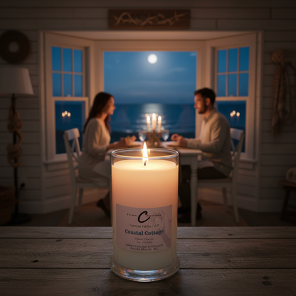 Coastal Cottage Soy Candle lit on a rustic table with a couple dining by the ocean at night.