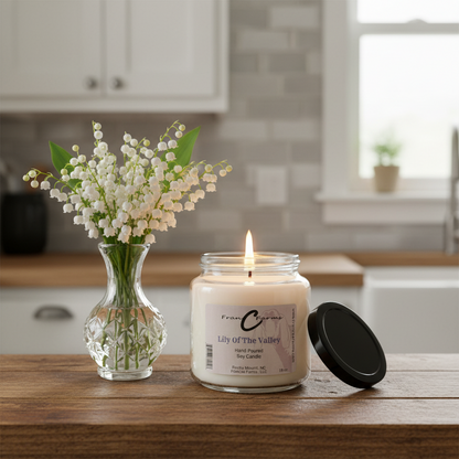 Lily of the Valley Soy Candle in apothecary jar next to a vase of lily of the valley flowers.