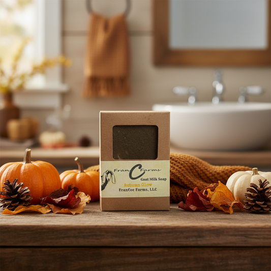 Autumn Glow Goat Milk Soap packaging on a wooden table with autumn decorations and a blurred bathroom background.