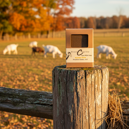 Autumn Glow Goat Milk Soap on a wooden post with goats grazing in a colorful autumn field.