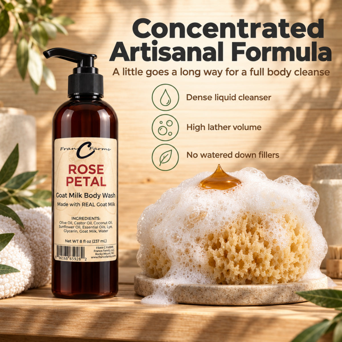 Rose Petal Goat Milk Body Wash concentrate beside a lather-covered bath sponge with a small amber dollop