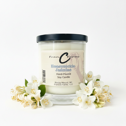Honeysuckle Jasmine Soy Candle in a jar surrounded by flowers, showcasing a floral fragrance.