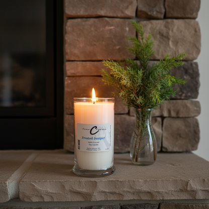 Frosted Juniper Soy Candle - 22 oz. in a stylish jar with a wooden fireplace backdrop.