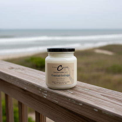 Coastal Cottage Soy Candle in an 18 oz. apothecary jar on a wooden deck by the beach.