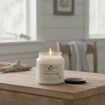 Coastal Cottage Soy Candle in apothecary jar, lit on a wooden table in a beachside inspired interior setting.